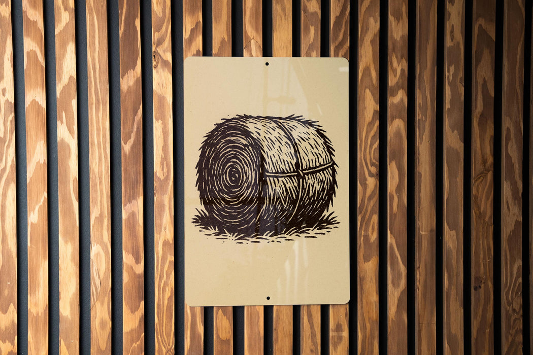 a sign with a black and white illustration of a hay bale on a wooden wall.