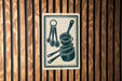 A sign with a pictogram of kitchen utensils, including measuring cups and spoons, mounted on a wooden wall.