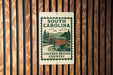 A sign for the Covered Bridge Country in South Carolina, featuring a wooden bridge and a scenic landscape.