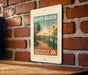 A poster of a riverwalk promenade in North Dakota, featuring a scenic image of a path lined with trees and lampposts, mounted on a brick wall.