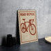 a sign with a bicycle on it, placed on a table next to some black camera lenses.