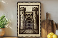 a framed illustration of a castle with two towers, placed on a shelf next to a wooden cutting board and a potted plant.
