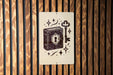 A sign with a key and a book illustration is displayed on a wooden wall.