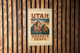 A sign for the Utah Granite Peaks, featuring a mountain illustration, is displayed on a wooden wall.