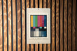 a colorful television antennae-like object mounted on a wooden wall.