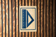 a sign with a blue triangle and a ruler on it, mounted on a wooden wall.