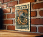 A metal sign with the text "IDAHO CRYSTAL CAVENS" is displayed on a brick wall.