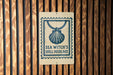 A sign for "Sea Witch's Shell Necklace" is displayed on a wooden wall.