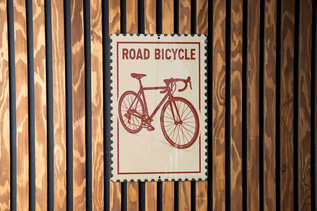 A sign that reads "ROAD BICYCLE" is displayed against a wooden wall.