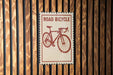 A sign that reads "ROAD BICYCLE" is displayed against a wooden wall.
