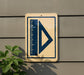 a sign with a blue triangle and a ruler on it, mounted on a wall.