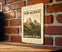 A metal sign with a mountain landscape and the text "NEW MEXICO GRAINITE PEAKS" is displayed on a brick wall.