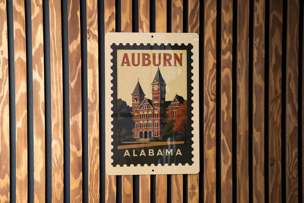 A vintage-style postage stamp from Alabama featuring a building with a clock tower, mounted on a wooden wall.