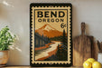 A vintage-style poster of Bend, Oregon, featuring a mountain landscape and a river, displayed on a wall next to a wooden cutting board and some lemons.