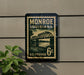A vintage-style postage stamp from Monroe, Louisiana, featuring a bridge and water, mounted on a wall.