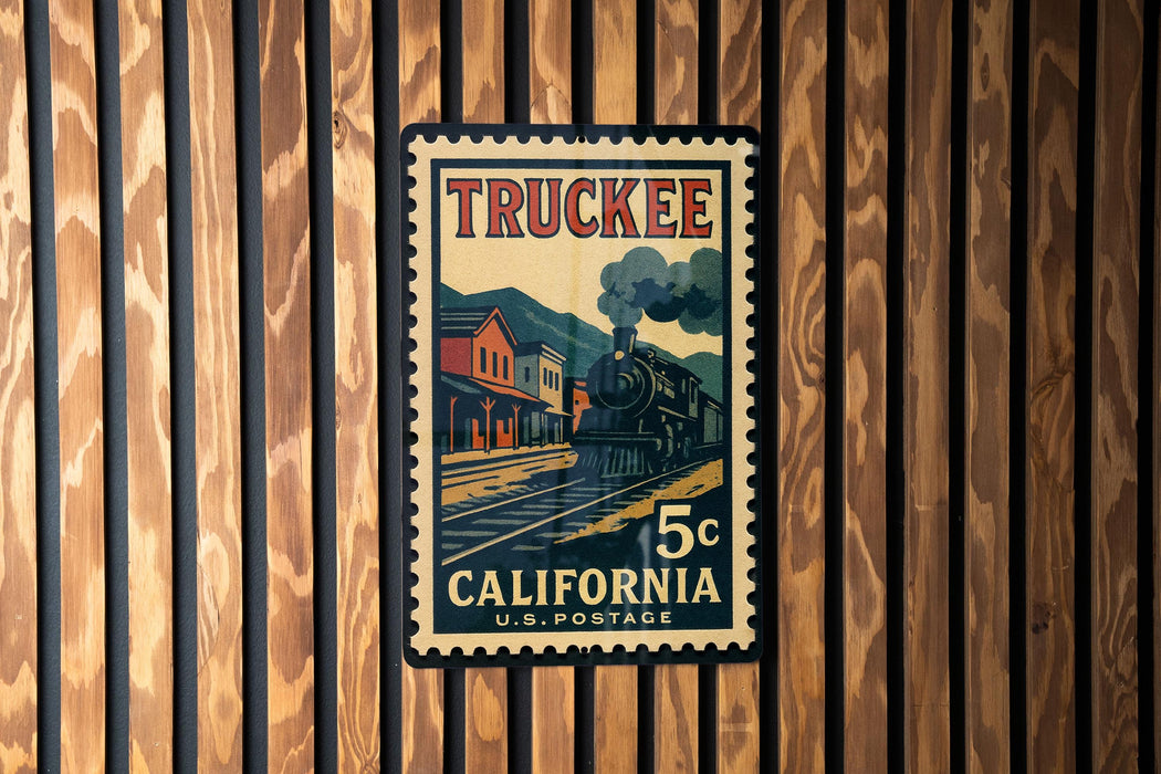 A vintage postage stamp from California, featuring a steam locomotive on the tracks, mounted on a wooden wall.