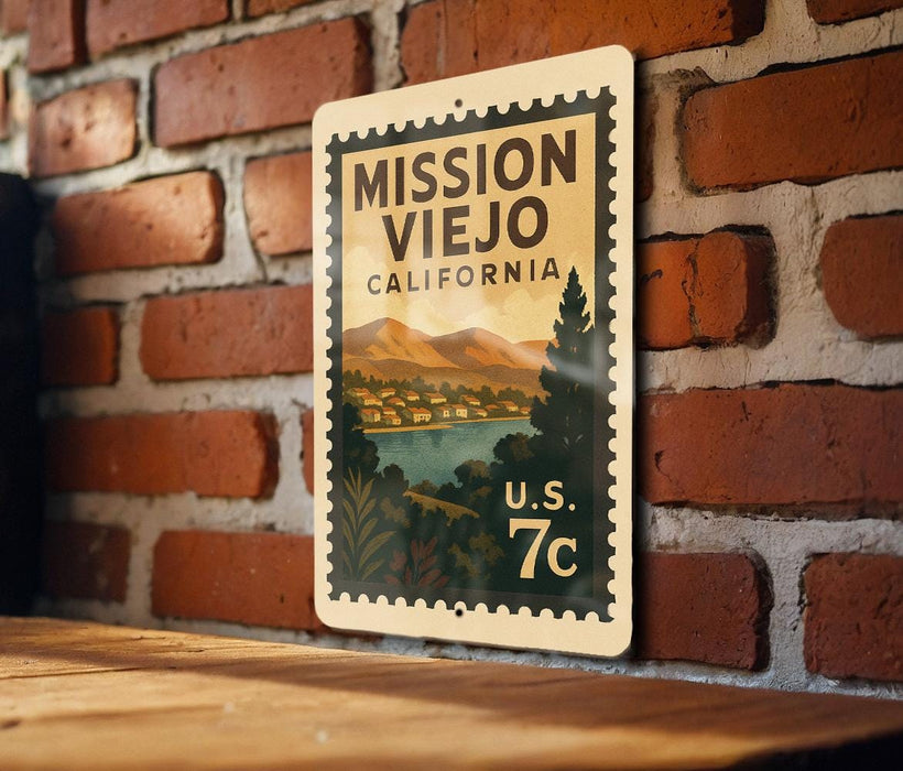 A metal sign with a vintage-style illustration of Mission Viejo, California, mounted on a brick wall.