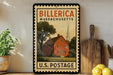A vintage-style stamp depicting a red brick house with a church steeple, placed on a shelf next to a wooden cutting board and a potted plant.