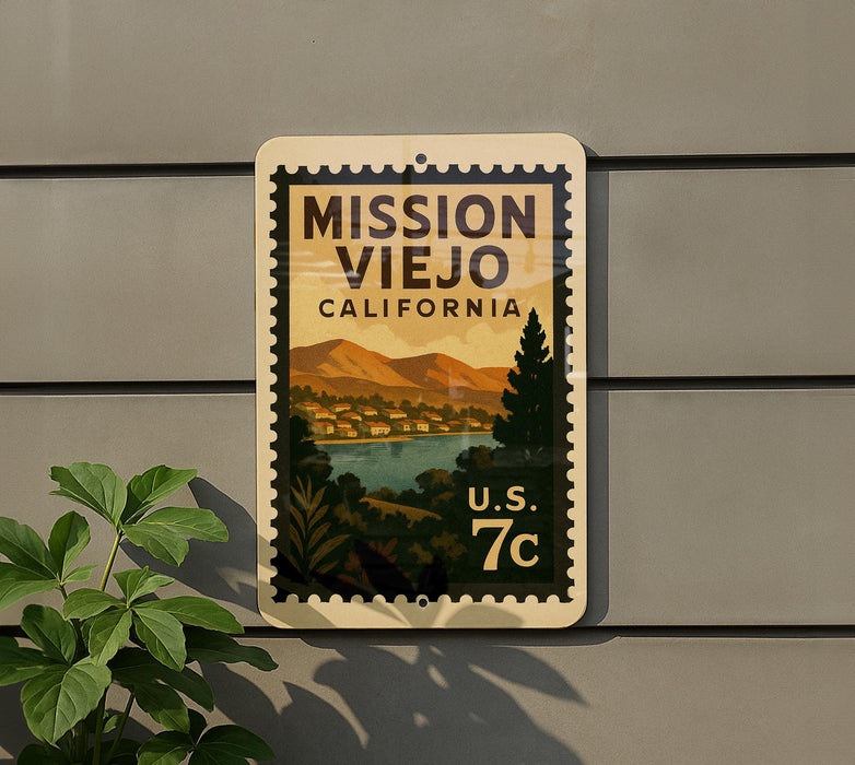 A vintage-style postage stamp depicting Mission Viejo, California, with a mountain landscape and a river, mounted on a wall.