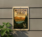A vintage-style postage stamp depicting Mission Viejo, California, with a mountain landscape and a river, mounted on a wall.