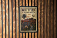 A vintage postage stamp from California, featuring a palm tree and a mountain landscape, is displayed on a wooden wall.