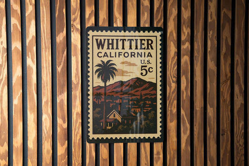 A vintage postage stamp from California, featuring a palm tree and a mountain landscape, is displayed on a wooden wall.