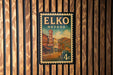 A vintage-style poster of the Elko, Nevada hotel, mounted on a wooden wall.