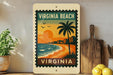 A vintage-style metal sign with a tropical beach scene, featuring a palm tree, ocean waves, and buildings, is displayed on a shelf next to a wooden cutting board and some potted plants.