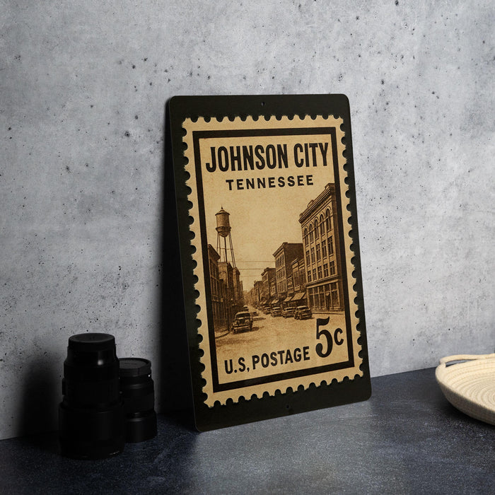 A vintage Johnson City, Tennessee postage stamp is displayed on a table, with a black camera lens and a woven basket nearby.