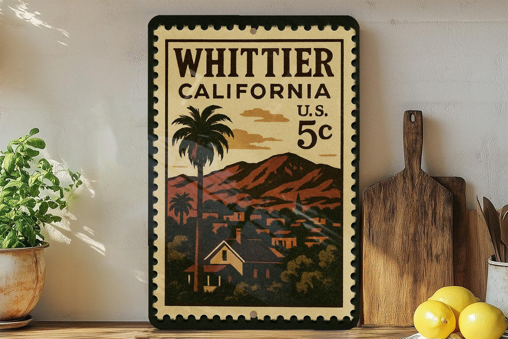 A vintage-style stamp depicting Whittier, California, with a palm tree and mountains in the background, placed on a shelf next to a wooden cutting board and some lemons.