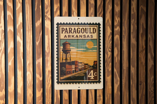 A vintage-style postage stamp from Arkansas featuring a water tower and buildings, mounted on a wooden wall.