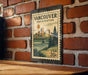 A vintage-style postage stamp from Vancouver, Washington, featuring a cityscape and a bridge, mounted on a brick wall.