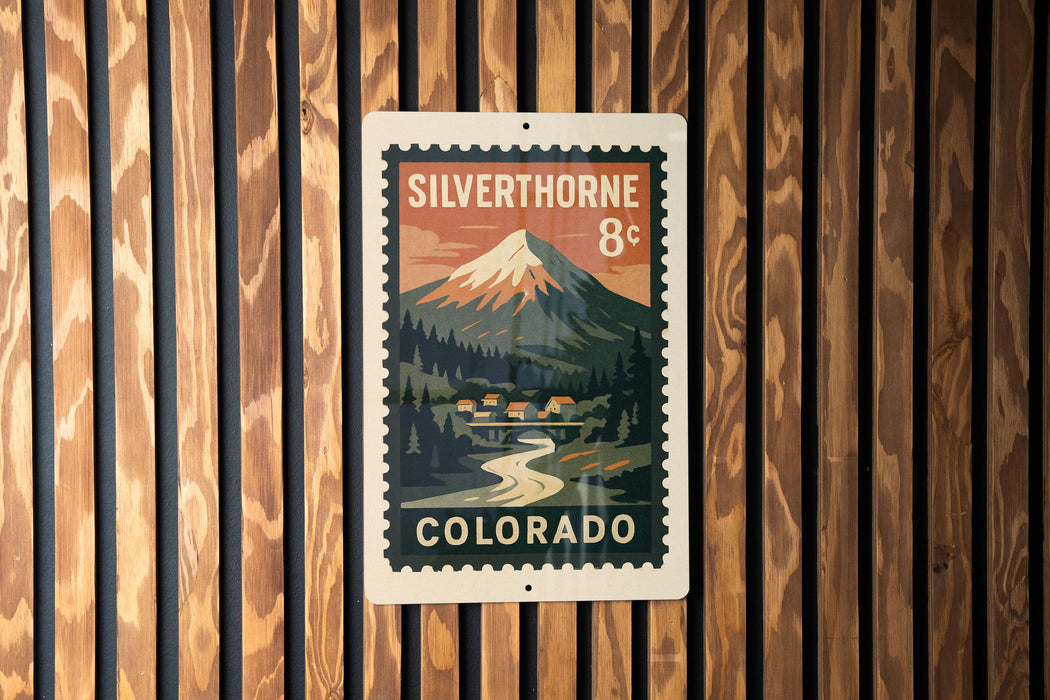 A vintage-style postage stamp from Colorado, featuring a mountain landscape and a small town, is displayed on a wooden wall.