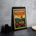A framed vintage postage stamp depicting the town of Harrisonburg, Virginia, with a clock tower and colorful buildings.
