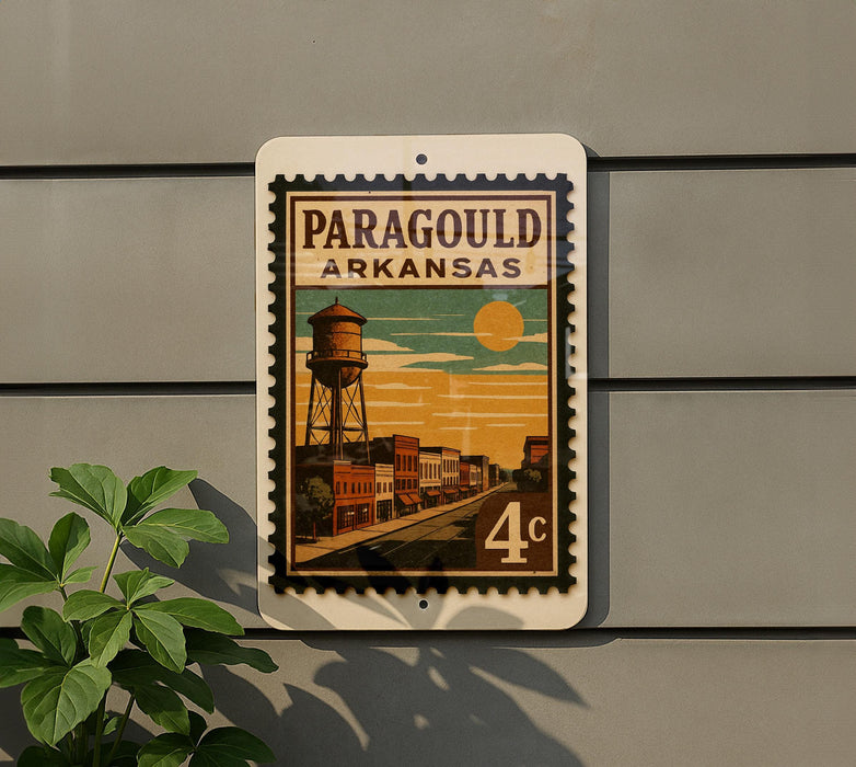 A vintage-style postage stamp from Arkansas featuring a water tower and a street scene, mounted on a wall.