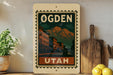 a vintage-style sign for Ogden, Utah, with a mountain landscape and buildings in the background.
