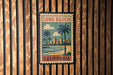A vintage-style stamp or sign with the text "LONG BEACH CALIFORNIA" and an illustration of a beach scene with palm trees and a city skyline.