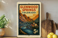 A vintage-style postage stamp depicting Glenwood Springs, Colorado, with a scenic mountain landscape and a bridge.
