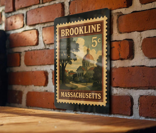 A vintage-style postage stamp from Massachusetts, featuring a building and trees, is displayed on a brick wall.