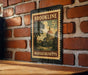 A vintage-style postage stamp from Massachusetts, featuring a building and trees, is displayed on a brick wall.