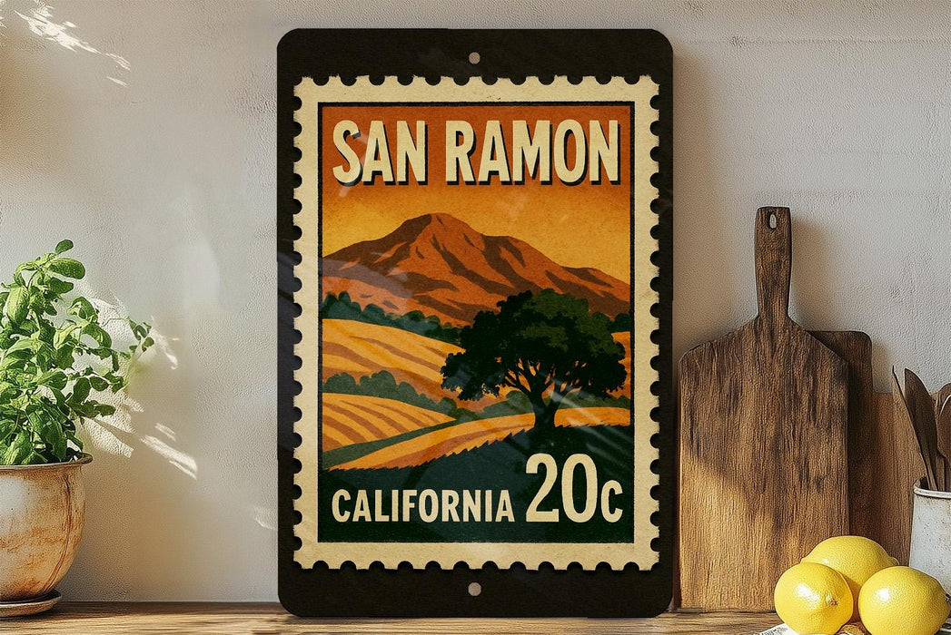 A framed poster of a scenic landscape with mountains and a tree, featuring the text "SAN RAMON" and "CALIFORNIA 20c" on it, is displayed on a shelf next to a wooden cutting board and some potted plants.