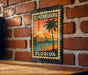 A vintage-style metal sign with a palm tree and sunset illustration, mounted on a brick wall.