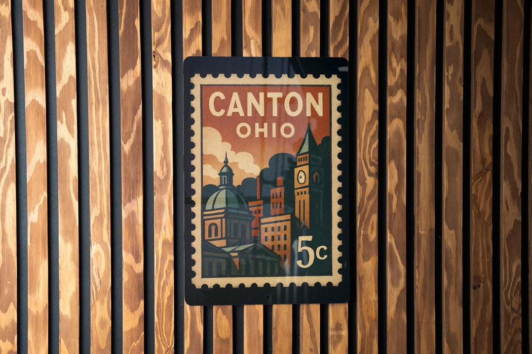 A postage stamp depicting Canton, Ohio, with a cityscape and a clock on a wooden background.