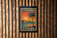 A vintage-style postage stamp depicting St. Petersburg, Florida, with a palm tree and sunset in the background.
