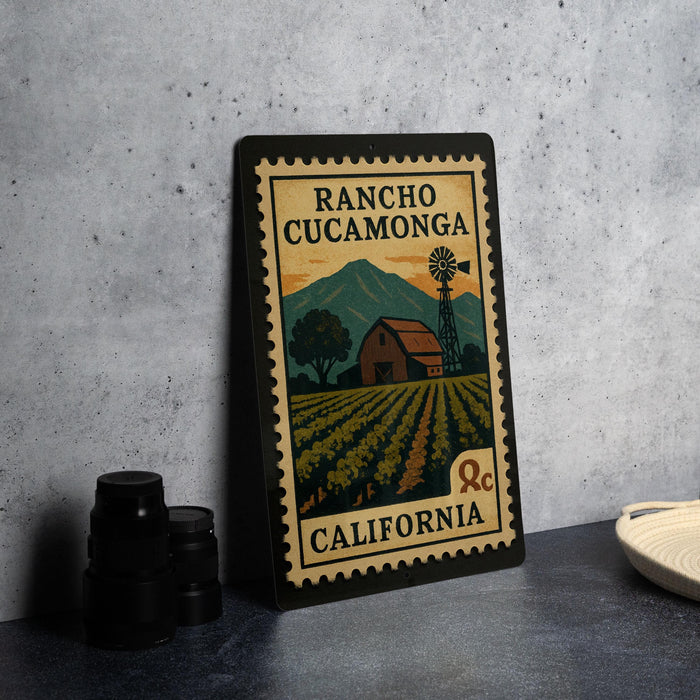 A framed poster of a rural scene with a windmill, barn, and field, depicting the location of Rancho Cucamona, California.