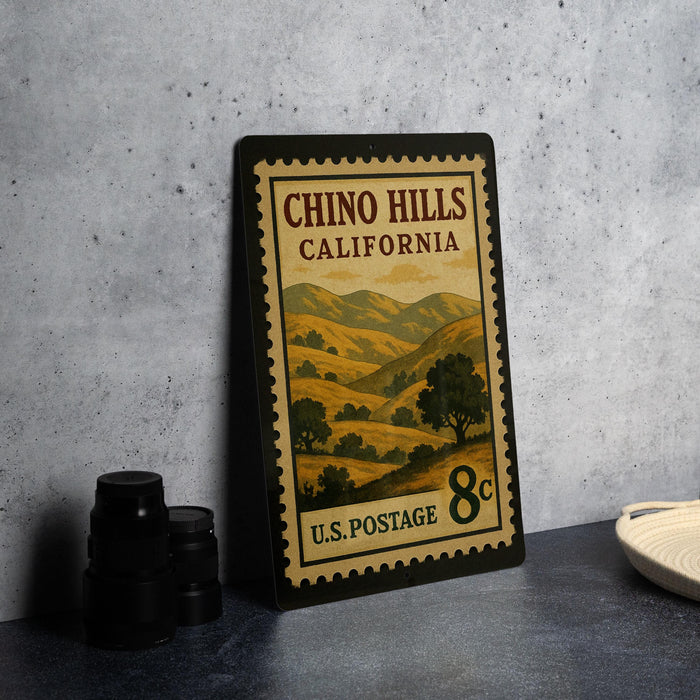 A vintage postage stamp from California, featuring a scenic landscape, is displayed on a table next to some black camera lenses.