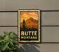 A vintage-style metal sign with a mountain and a tower in the background, mounted on a wall.