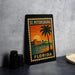 A framed poster of St. Petersburg, Florida, featuring a palm tree and a sunset over the water, is displayed on a countertop.