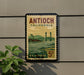 A vintage postage stamp from California, featuring a bridge and a river, mounted on a wall.