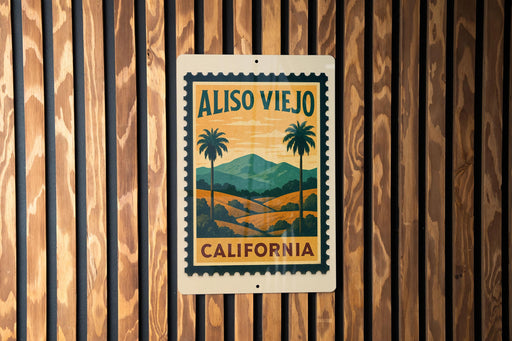 A vintage-style metal sign with the text "ALISO VIERO CALIFORNIA" and palm trees, mounted on a wooden wall.